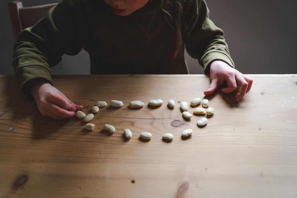 A child using hand-eye co-ordination to position a dried bean in a circle