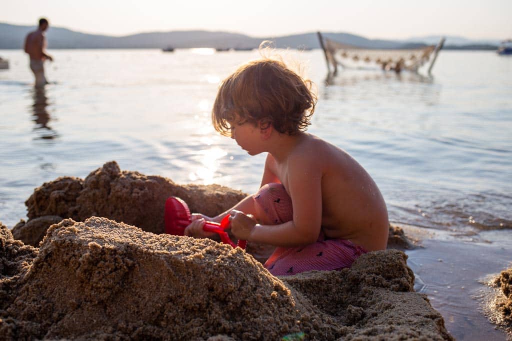 A boy playing with sand and water at the beach