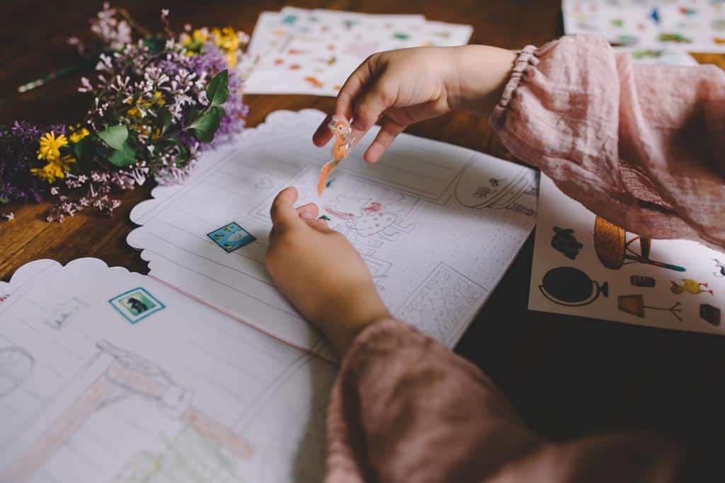 A child applying a sticker to a page