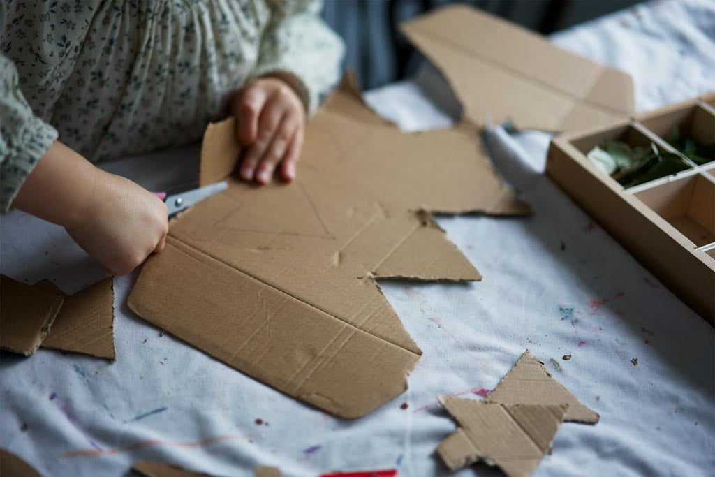 A child cutting Christmas tree decorations out of cardboard