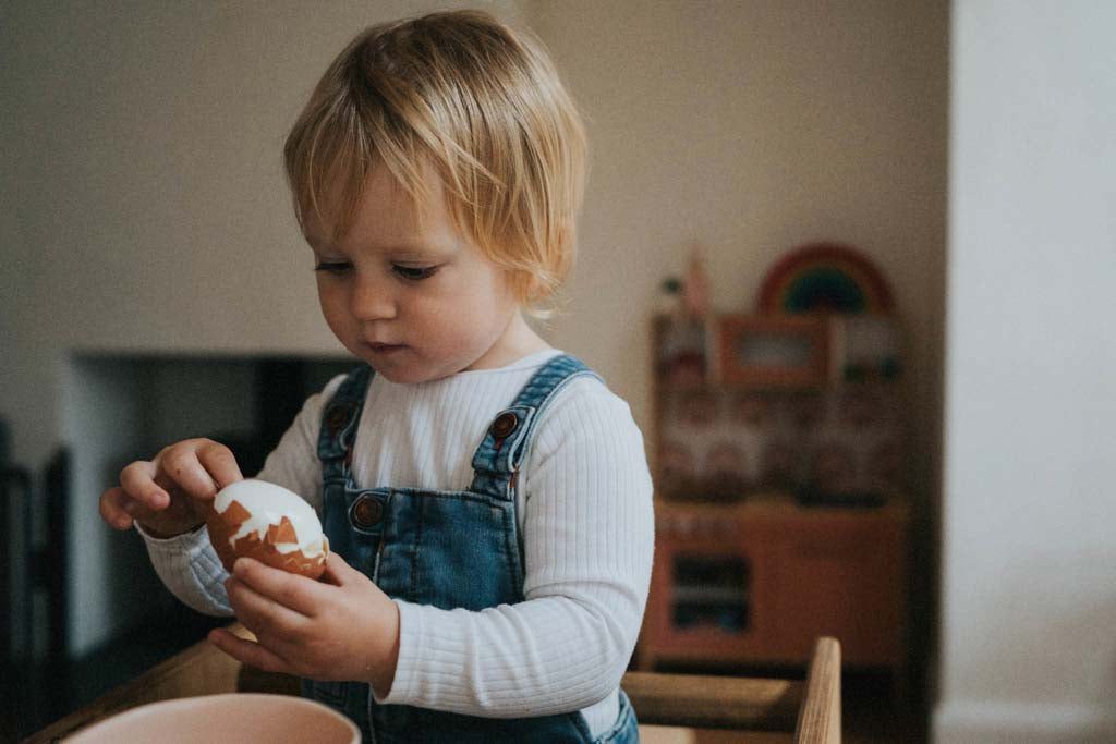 A child peeling an egg