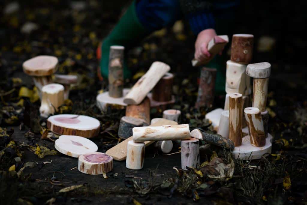 A child building with sections of tree trunks and branches