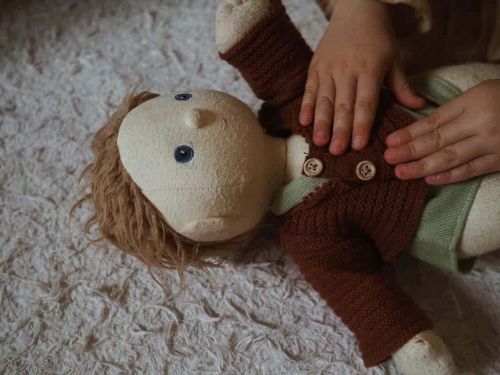 A child engaging in symbolic play by dressing a doll