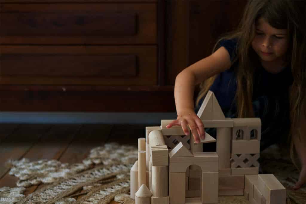 A child making an enclosure with wooden building blocks