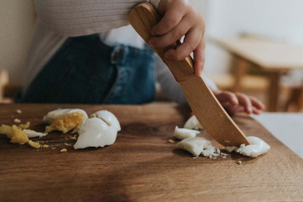 A child using a safe knife to cut an egg