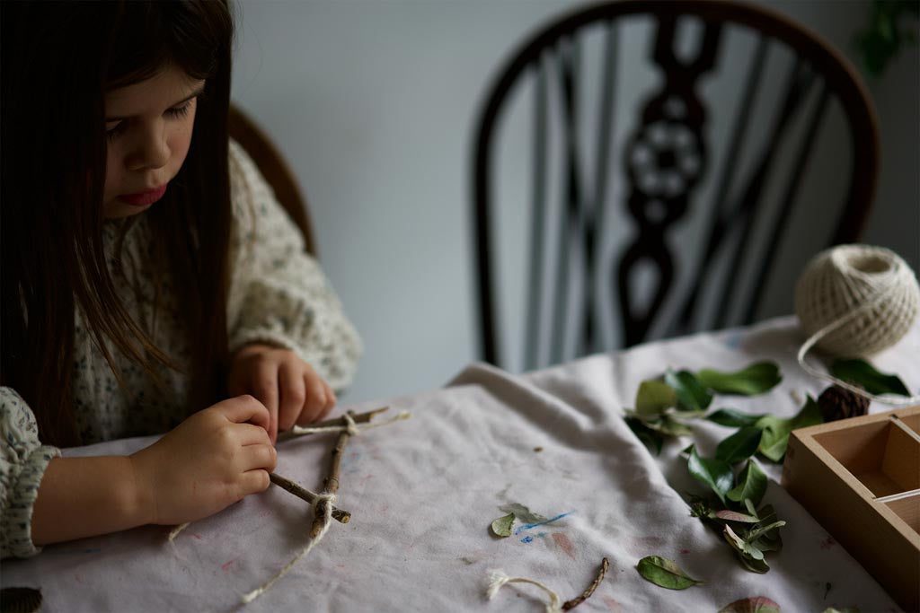 A child binding sticks together to make a Christmas star decoration